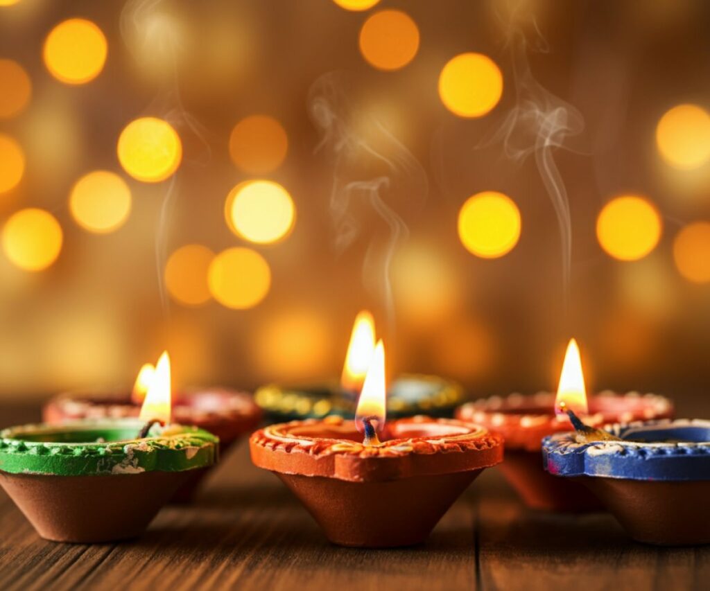 A row of lit clay oil lamps, or diyas, glowing brightly during the Deepavali festival.